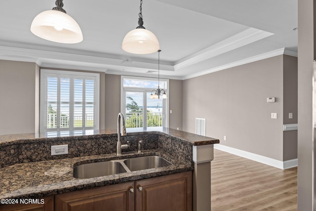 kitchen with dark stone countertops, ornamental molding, hardwood / wood-style flooring, and sink