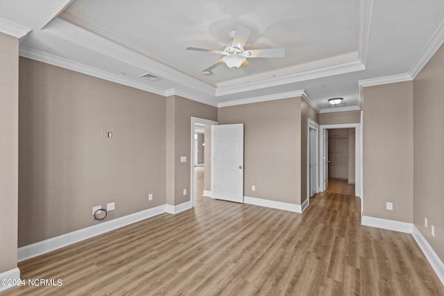 spare room featuring hardwood / wood-style floors, a tray ceiling, crown molding, and ceiling fan