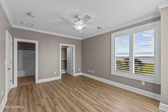 unfurnished bedroom featuring crown molding, ceiling fan, a spacious closet, and light hardwood / wood-style floors