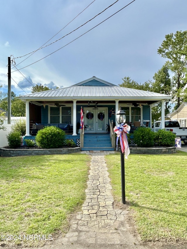 view of front facade featuring metal roof, a porch, and a front lawn