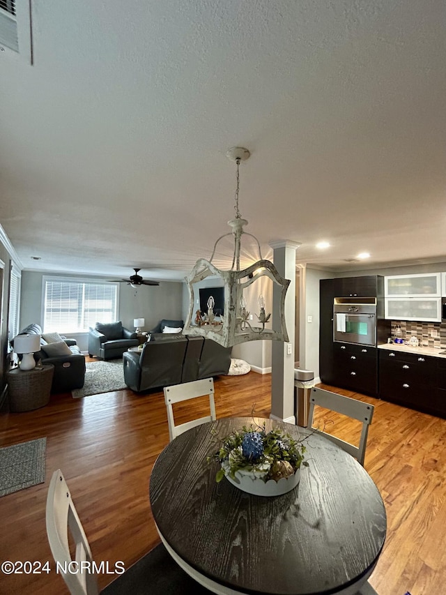 dining room featuring a textured ceiling, ceiling fan, ornamental molding, and light wood-style flooring