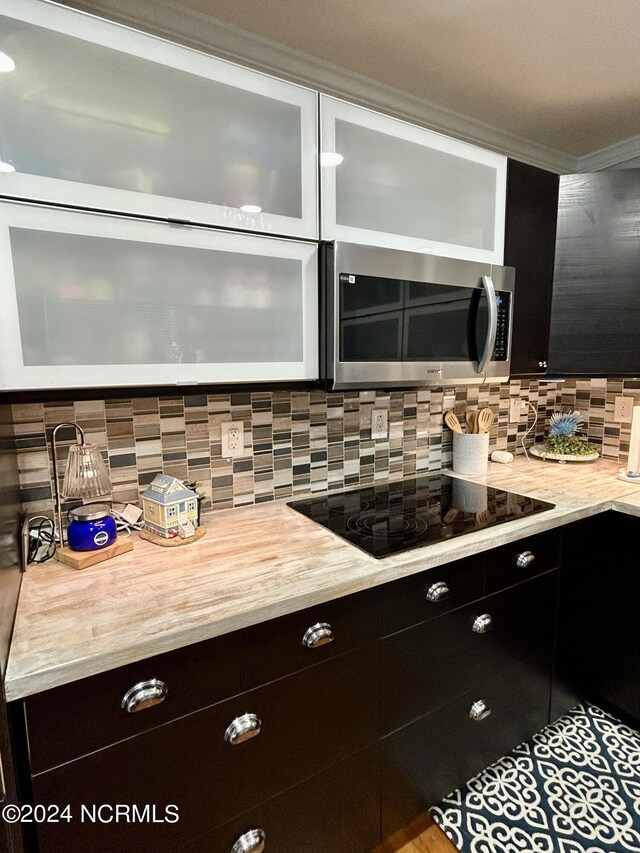 kitchen with black electric stovetop and tasteful backsplash