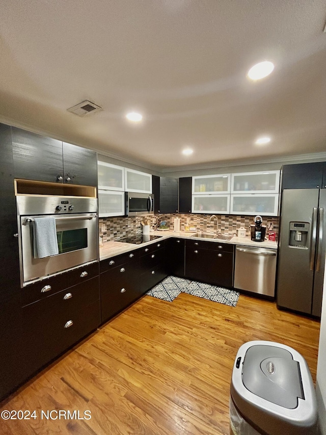 kitchen featuring light wood finished floors, visible vents, glass insert cabinets, appliances with stainless steel finishes, and a sink