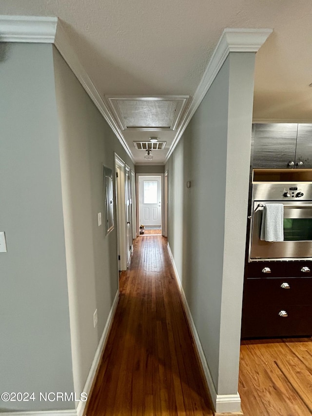 corridor featuring baseboards, visible vents, ornamental molding, and wood finished floors