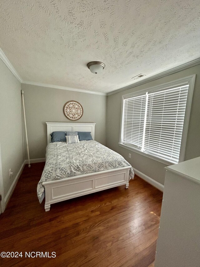 bedroom featuring a textured ceiling, dark wood-type flooring, and ornamental molding