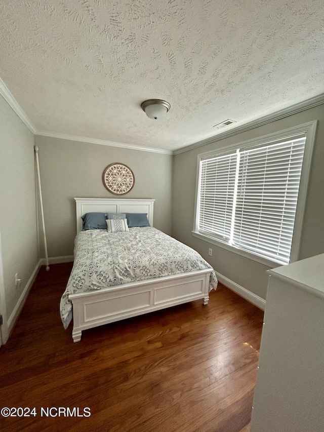 bedroom featuring baseboards, visible vents, dark wood-style flooring, crown molding, and a textured ceiling