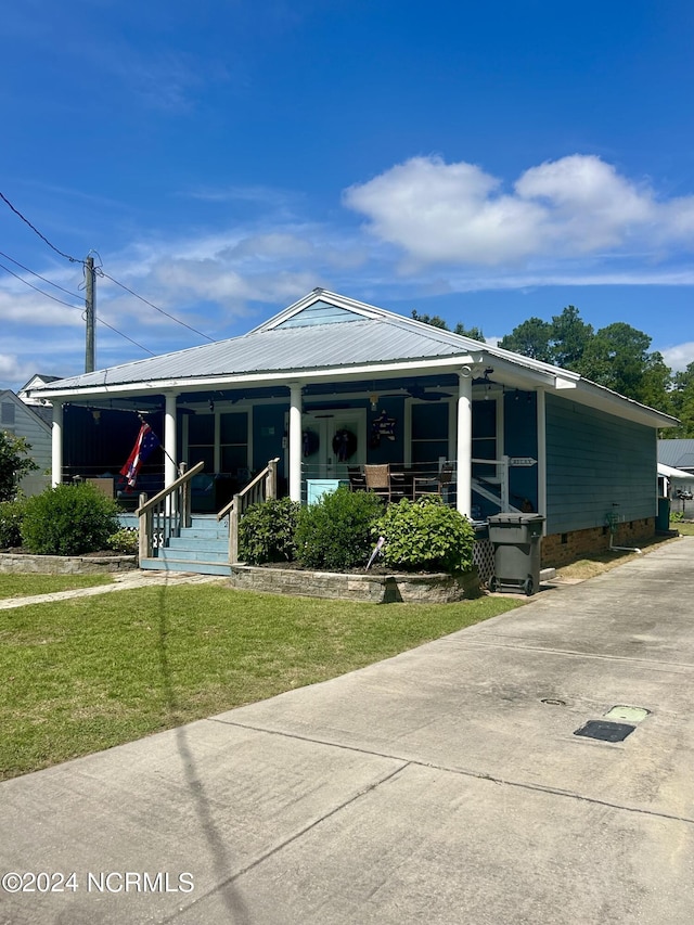 view of front of house with crawl space, covered porch, metal roof, and a front lawn