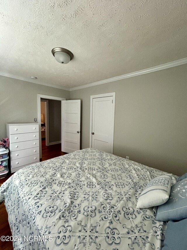 bedroom with hardwood / wood-style floors, ornamental molding, and a textured ceiling