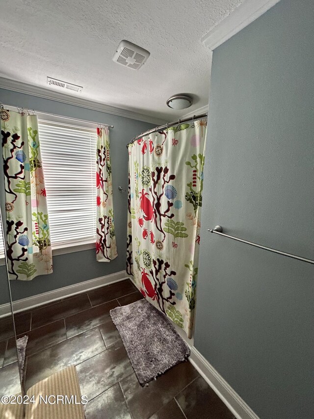 bathroom featuring ornamental molding, a textured ceiling, and a shower with shower curtain