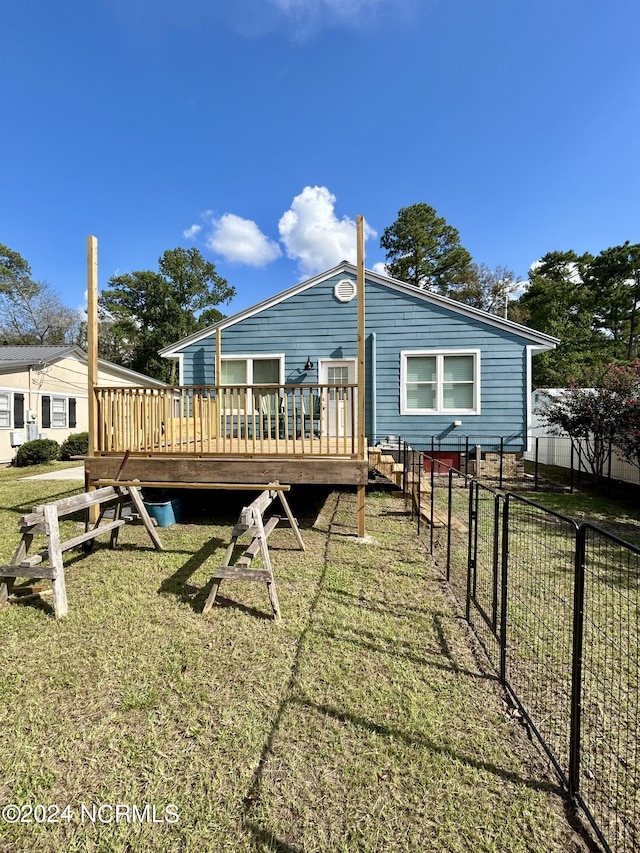 back of property with a deck, a lawn, and fence