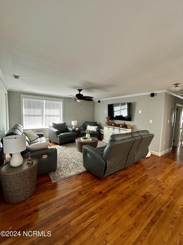 living room with crown molding, dark wood-type flooring, and ceiling fan