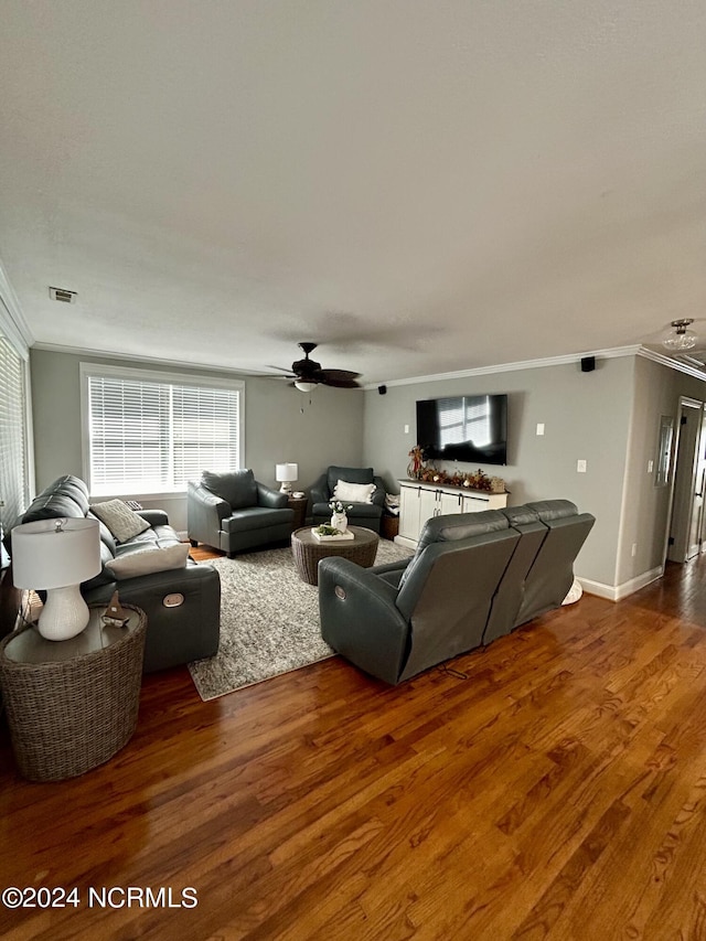 living area with visible vents, ornamental molding, a ceiling fan, wood finished floors, and baseboards