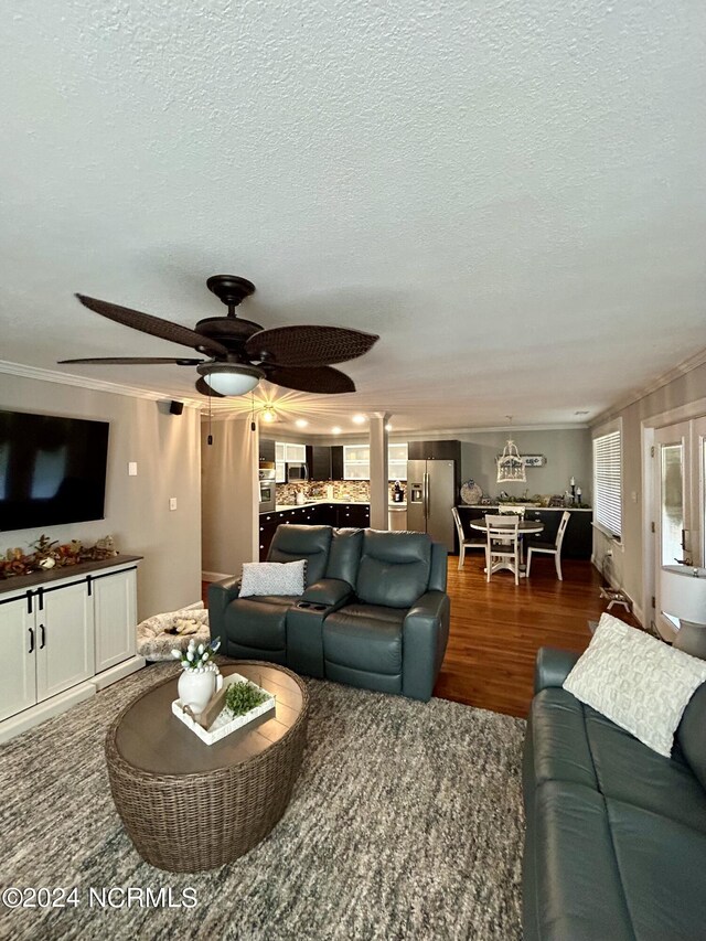 living room featuring ceiling fan, dark hardwood / wood-style floors, crown molding, and a textured ceiling