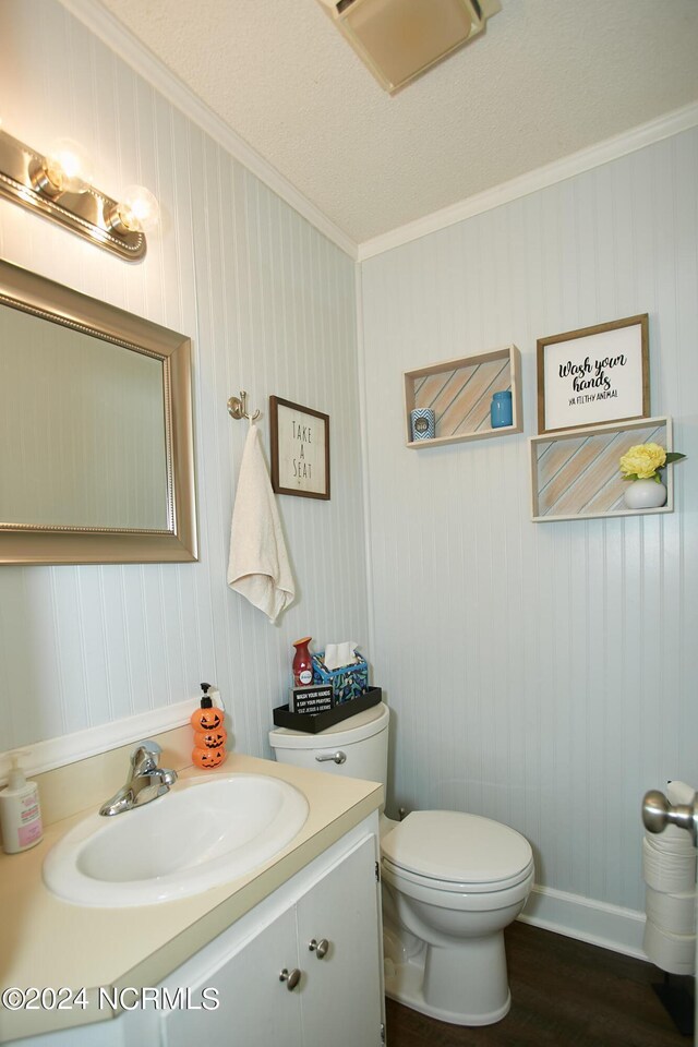 bathroom featuring wood finished floors, vanity, toilet, and crown molding