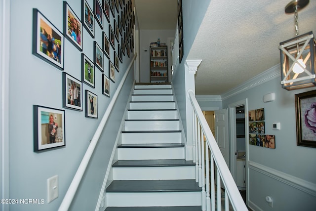 stairs featuring a textured ceiling and crown molding