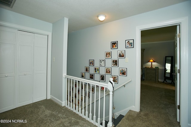 corridor with baseboards, carpet flooring, visible vents, and an upstairs landing