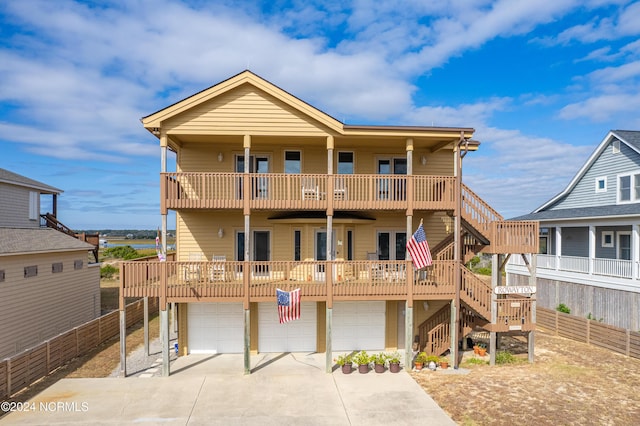 view of front of home with driveway, fence, an attached garage, a balcony, and stairway