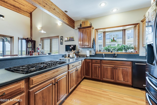 kitchen with dark countertops, black appliances, a sink, and beamed ceiling