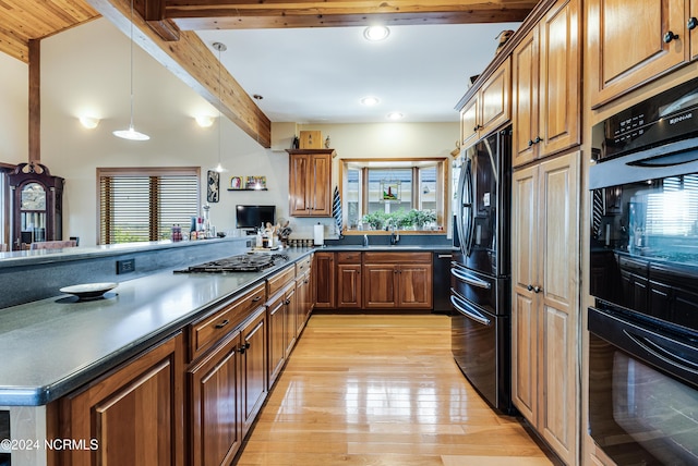 kitchen with beamed ceiling, sink, hanging light fixtures, black appliances, and light hardwood / wood-style flooring