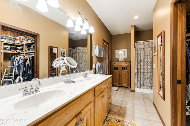 bathroom with double vanity, tile patterned flooring, a spacious closet, and a sink