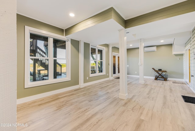 interior space with baseboards, a wall unit AC, ornate columns, and wood finished floors