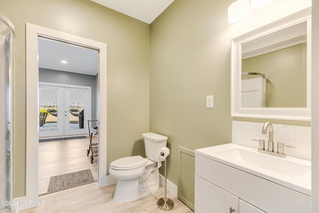 bathroom with french doors, walk in shower, toilet, vanity, and hardwood / wood-style floors