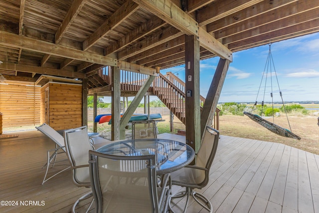 wooden terrace with outdoor dining space and stairway