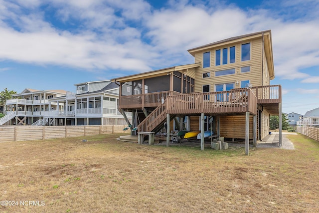 rear view of house with a lawn, stairway, a sunroom, fence, and a deck