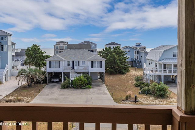 exterior space with a balcony, stairs, concrete driveway, a residential view, and a carport