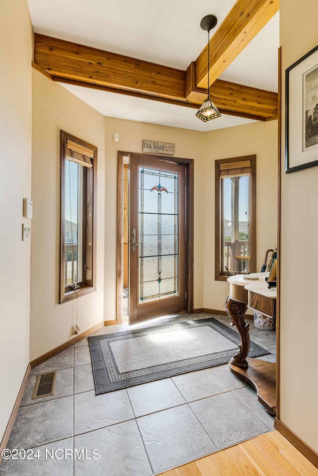 tiled foyer featuring beam ceiling