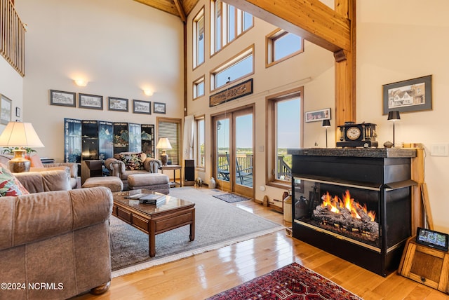 living room with a multi sided fireplace, baseboards, french doors, beam ceiling, and wood-type flooring