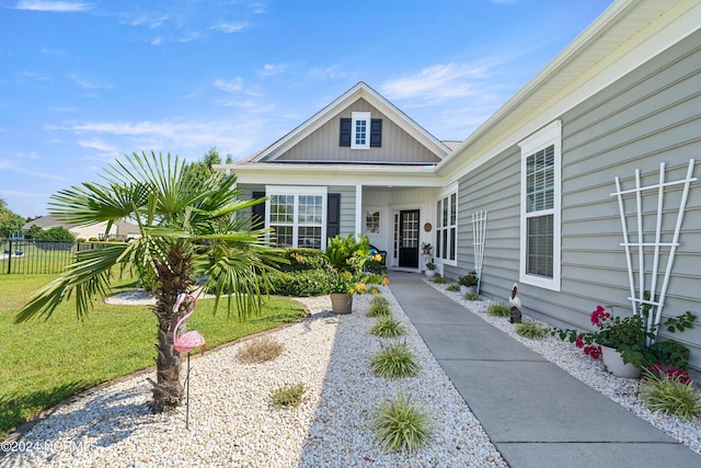 entrance to property featuring board and batten siding, a yard, and fence