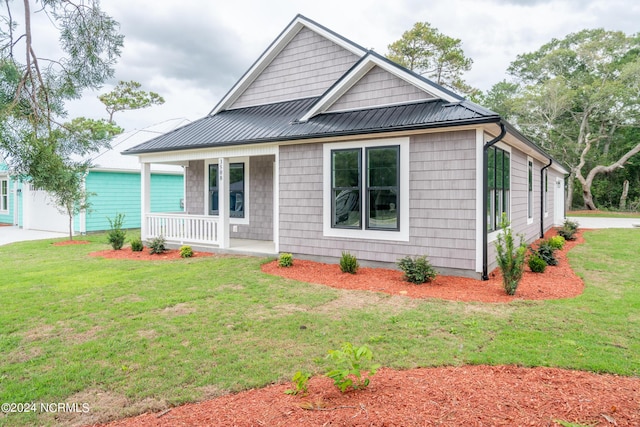 view of front of home with a garage, metal roof, a porch, and a front yard