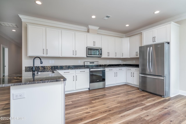 kitchen with a peninsula, a sink, visible vents, appliances with stainless steel finishes, and crown molding