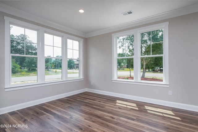 unfurnished room with baseboards, visible vents, dark wood-style flooring, and crown molding