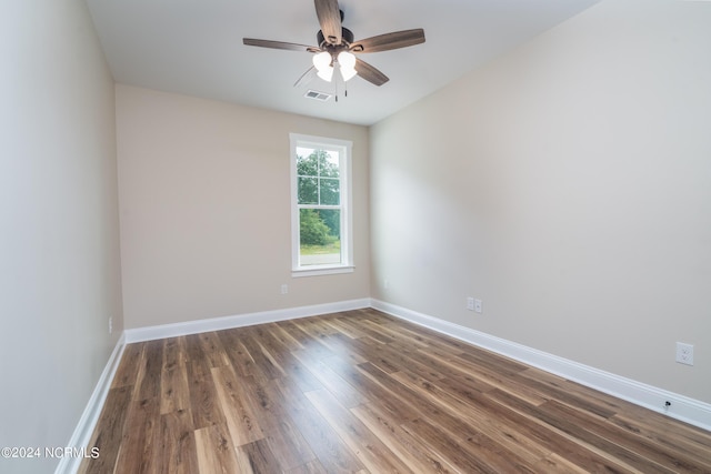 empty room with baseboards, visible vents, a ceiling fan, and wood finished floors