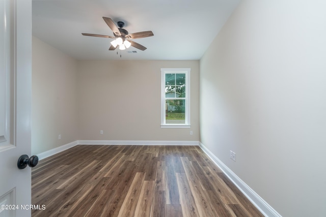 empty room with dark wood-style floors, visible vents, baseboards, and a ceiling fan