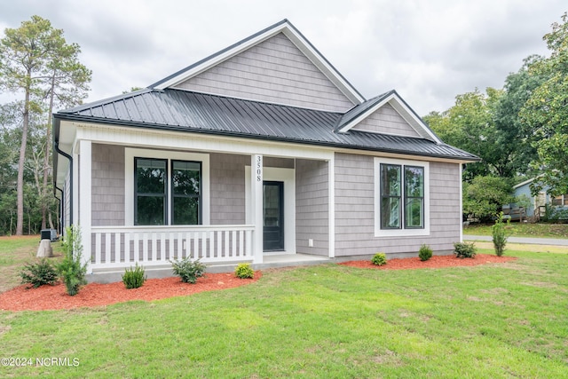 view of front of property featuring covered porch, metal roof, and a front lawn