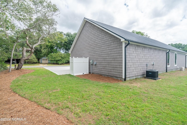 view of home's exterior with fence, central AC unit, metal roof, and a lawn