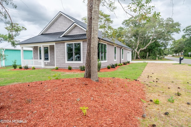 view of front of home featuring metal roof, a porch, a standing seam roof, and a front yard