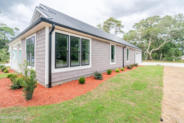 view of side of home with metal roof and a yard