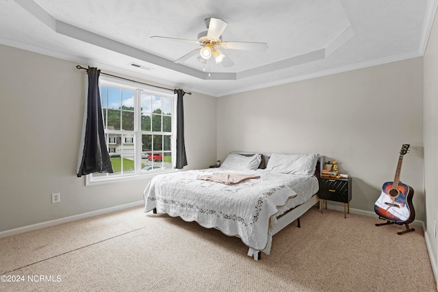 bedroom featuring carpet flooring, ornamental molding, ceiling fan, and a raised ceiling