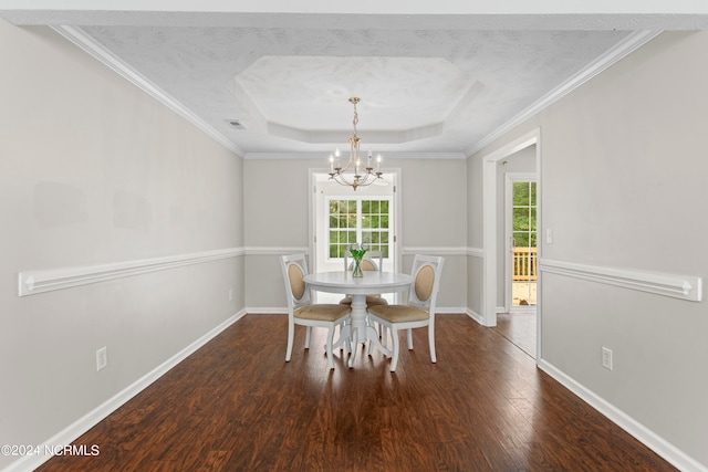 unfurnished dining area with dark hardwood / wood-style flooring, a textured ceiling, a chandelier, ornamental molding, and a raised ceiling