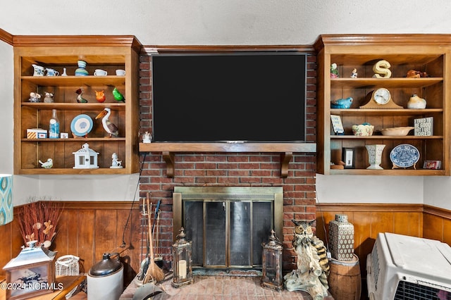 living room featuring a textured ceiling, a fireplace, and wood walls