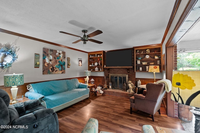 living room with ceiling fan, a brick fireplace, wood-type flooring, a textured ceiling, and crown molding