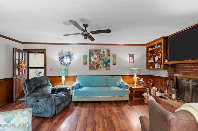 living room with ceiling fan, ornamental molding, wooden walls, a fireplace, and dark hardwood / wood-style flooring