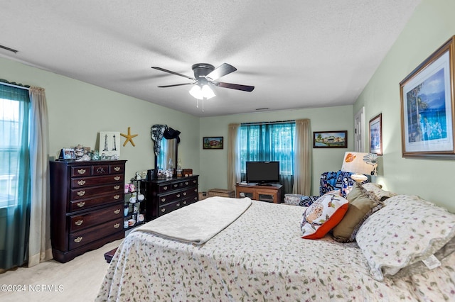 carpeted bedroom with ceiling fan and a textured ceiling