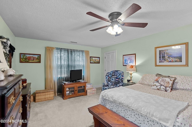 bedroom featuring a textured ceiling, ceiling fan, and light colored carpet