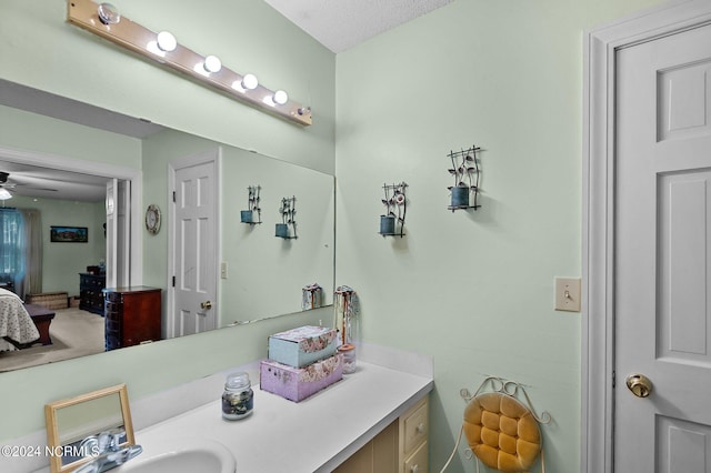 bathroom with ceiling fan, vanity, and a textured ceiling