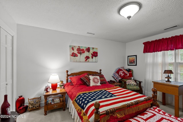 bedroom with a textured ceiling, carpet flooring, and a closet